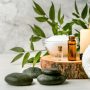 beauty treatment items for spa procedures on white wooden table. massage stones, essential oils and sea salt. copy space